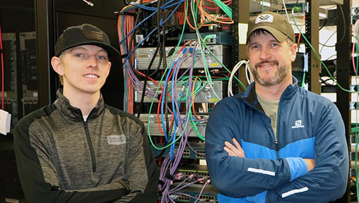 Two Men Standing in front of a server rack