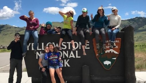 Students are posing with the Yellowstone national park sign.