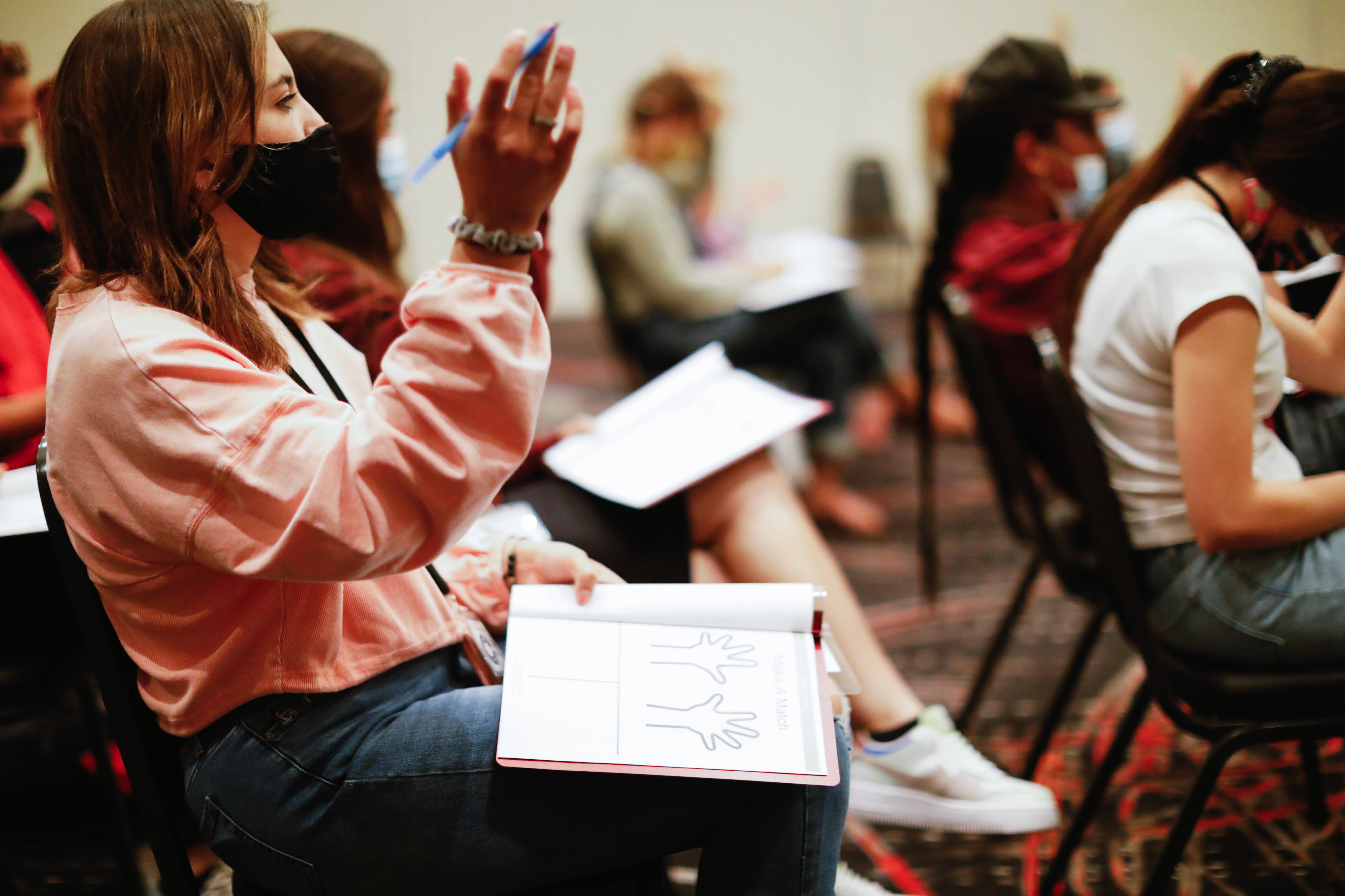 Student in classroom raising her hand